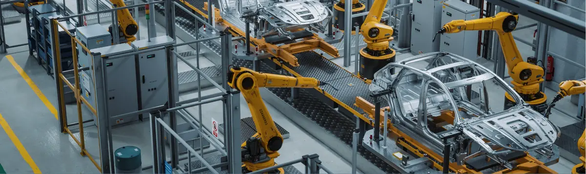 Robotic arms assembling car body frames on an automated production line inside a modern automotive facility