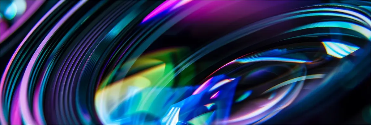 Abstract neon waves in pink, blue, and green flowing across a dark background with smooth motion blur effects